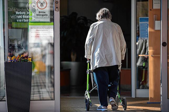 Eine Seniorin betritt mit ihrer Gehhilfe den Eingang ihres Seniorenheims. Hier gelten besonders strenge Regeln.