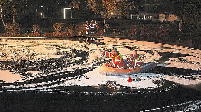 Die Feuerwehr bringt auch mit Hilfe eines Bootes Ölbindemittel auf dem Mühlenweiher im Kurpark aus. Dabei gleicht der Weiher teilweise ...