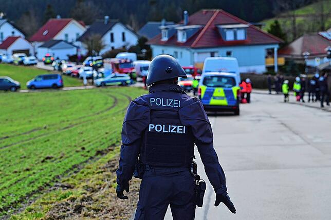 Ein Polizeibeamter mit Schutzhelm sperrt eine Zufahrt zu Unterkirnach am 23. Januar 2024 ab.