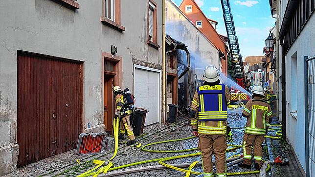 Ein Feuerwehrmann mit Atemschutz und Löschschlauch betritt ein Nachbargebäude.