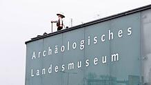 (Archivbild) Das große Playmobilmännchen auf dem Archäologischen Landesmuseum – hier eine Aufnahme von 2023 – blickt in Konstanz auf den ...