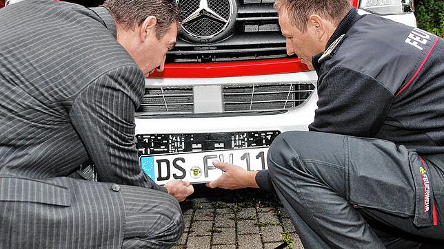 Oberbürgermeister Erik Pauly (links) und Kommandant Gerd Wimmer montieren ihr erstes DS-Kennzeichen gemeinsam an einem Einsatzfahrzeug.
