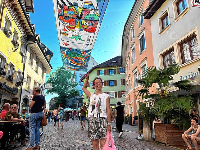 Künstlerin Sandra Wischnewski zeigt stolz auf ihr Kunstwerk „Der Joker“. Er hängt auf der Höhe zum Café IKII.