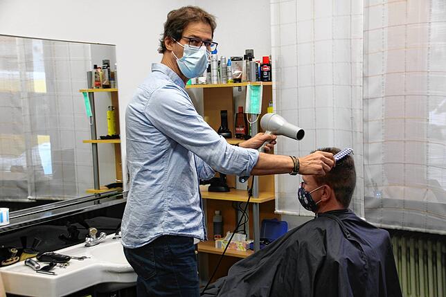 Christian Götz föhnt einem Kunden in seinem Salon die Haare. Ab Mittwoch muss er schließen.