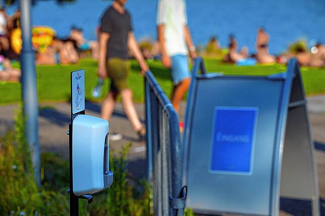 Hinter der Absperrung: Desinfektion, Masken und Abstandsregeln. Draußen: Badevergnügen nach Augenmaß