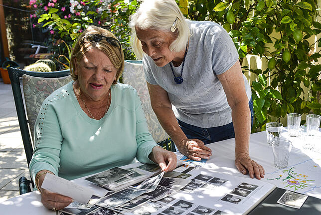 Jeannine Casey (links) betrachtet alte Fotos bei der Historikerin Christa Tholander in Friedrichshafen.