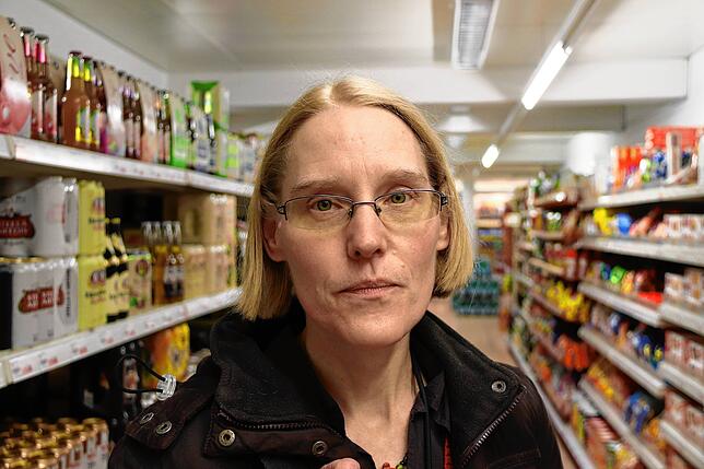 Andrea Fleckner auf einem Gang in einem Supermarkt zwischen hunderten Produkten.