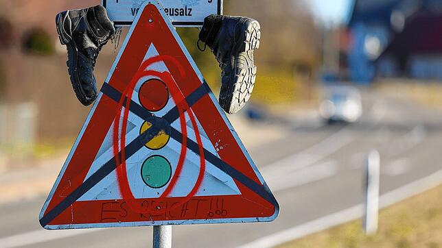 Ein durchgestrichenes Ampel-Verkehrsschild mit Schuhen hängt unterhalb des Ortschildes von Harthausen.