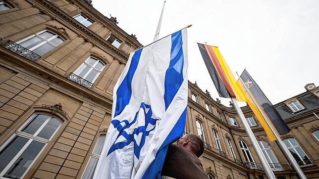 Die Flagge Israels wird von einem Mitarbeiter des Staatsministeriums in Stuttgart zwischen den Flaggen der EU, Deutschlands und ...
