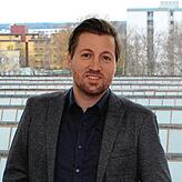 Tobias Fauth am Fenster des Cyberlago-Büros in der Farm, im Hintergrund die unter Denkmal stehende Fabrikhalle des Bückleareals.