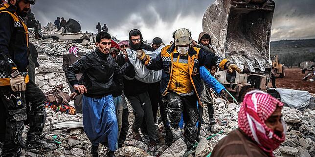 Zivilisten und Mitglieder des syrischen Zivilschutzes führen Such- und Rettungsmaßnahmesuchen in Harem durch.