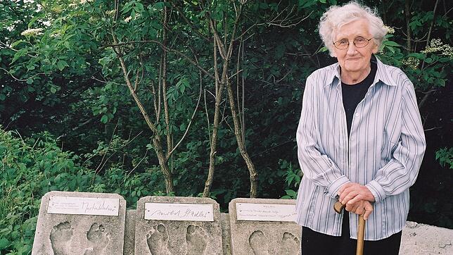 Maria Beig neben Fußabdrücken von Martin Walser, Arnold Stadler und sich selbst auf dem Höchsten im Linzgau. Bild: Kulturbüro FN