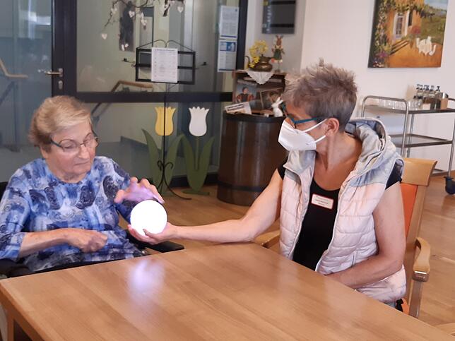Betreuerin Gudrun Bernauer (rechts) gibt den Therapie-Ball an Bewohnerin Gertrud Schilling weiter.