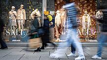 Menschen eilen an einem festlich geschmückten Schaufenster vorbei. Das große Angebot bietet Vor-, aber auch Nachteile.
