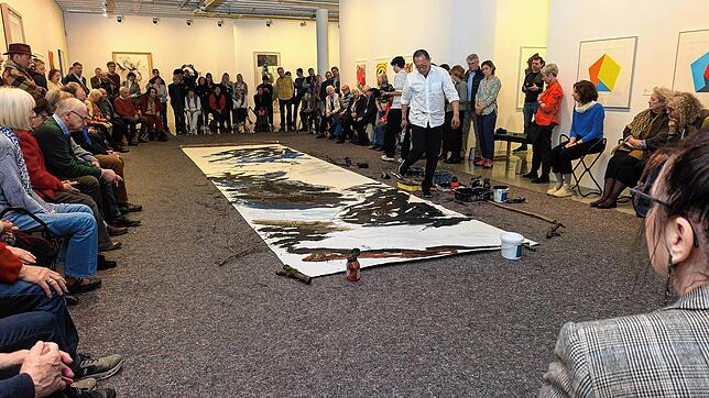 Xianwhei Zhu arbeitet im Kunstmuseum Singen umrahmt vom Publikum an einer abstrakt-gegenständlichen Basis aus Schwarz-, Grau- und ...