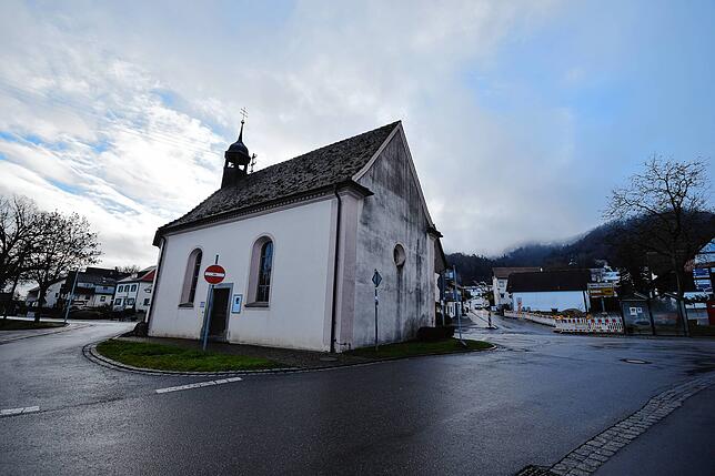 Die Kapelle steht mitten im Straßendreieck der Straße „Im Weiler“ (vorne) sowie der an ihrem Standort gespalteten ...