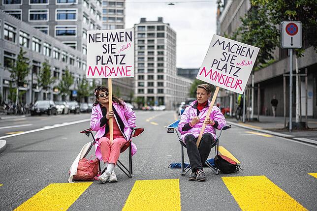 Im Juni 2020 halten zwei Frauen bei einer Sitzblockade in Zürich Schilder mit Protestslogans hoch.