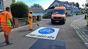 Im Schießstattweg werden am Donnerstagvormittag auf der Fahrbahn die Piktogramme aufgebracht.