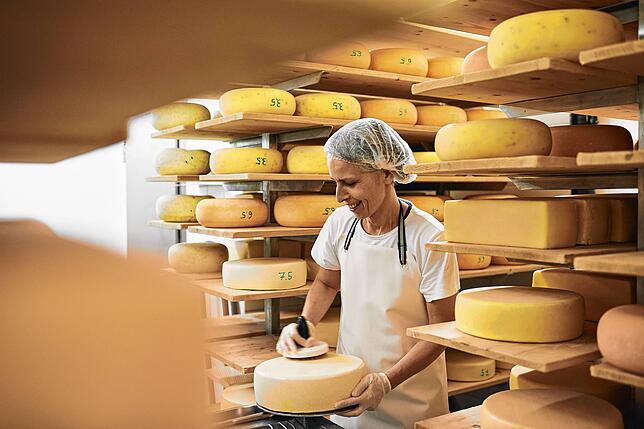 Mitarbeiterin Simone Rayher in der Käserei des Lehenhof beim sogenannten Käse schmieren.