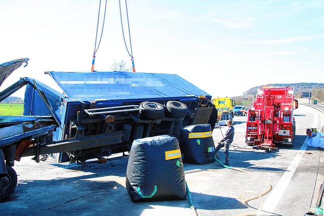 Lastwagen und Anhänger werden mit einem Schwerlastkran angehoben und mit speziellen Luftkissen als Puffer beim Kippen wieder aufgerichtet.