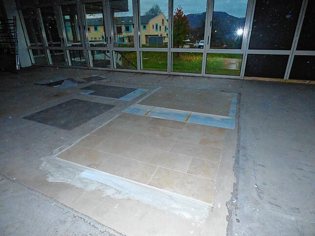 An einigen Stelle im Erdgeschoss sind für die künftigen Mieter Flächen mit Musterfliesen zum Aussuchen ausgelegt. Durch das Fenster ...