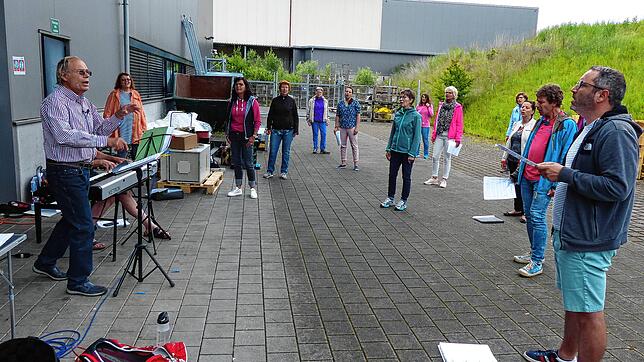 Und Action! Das Singen im Freien funktioniert &ndash; wenn man den Willen und eine Gebäudewand im Hintergrund hat. Links Chorleiter ...