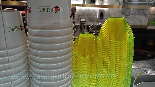 Neue Becher aus Papier und alte aus Plastik im Eiscafé Pinocchio: Die Restbestände an Plastikbechern dürfen noch aufgebraucht werden.