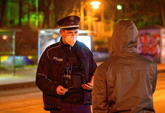 Polizisten laufen in der Nacht in Dresden Streife und kontrollieren die Einhaltung der Ausgangssperre.