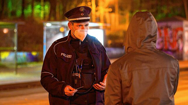 Polizisten laufen in der Nacht in Dresden Streife und kontrollieren die Einhaltung der Ausgangssperre.