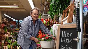 Ulrike Stöckle am Eingang ihres Blumengeschäfts. Der gusseiserne Stuhl ist verschwunden, der dazugehörige Tisch (rechts neben ihr) noch da.