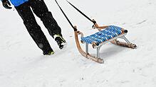 Ein Mann zieht seinen Schlitten über den Schnee (Symbolbild): Zu einem Unfall mit einem Verletzten ist es am Freitag auf einer Skipiste ...