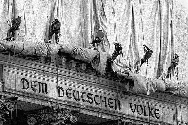 Arbeiten zur Reichstagsverhüllung 1995: Gewerbekletterer rollen die Verhüllungsplanen für den Berliner Reichstag vom Giebel des Bauwerks ab.