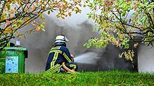 Ein Feuerwehrmann spritzt am Montag mit einem Strahlrohr Wasser in den brennenden Raum.