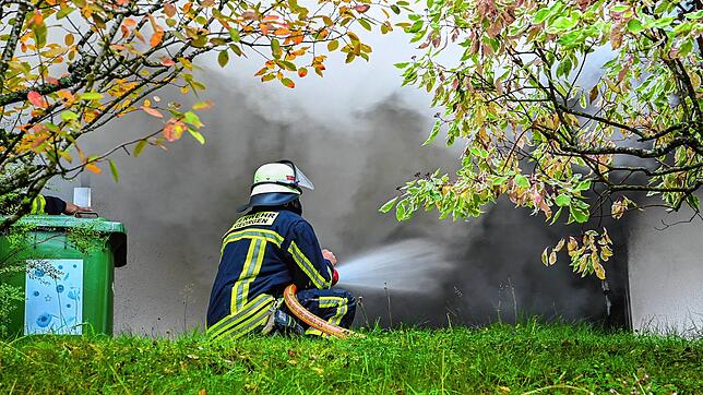 Ein Feuerwehrmann spritzt am Montag mit einem Strahlrohr Wasser in den brennenden Raum.