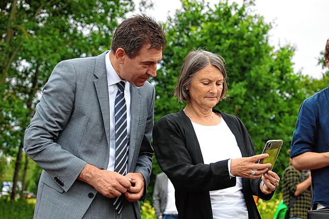 Oberbürgermeister Erik Pauly und Regierungspräsidentin Bärbel Schäfer probieren die neue App für den Zusammenfluss aus.
