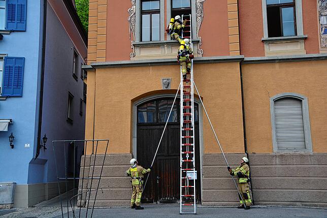 Über die Steckleiter steigen die Feuerwehrleute in den ersten Stock, um die dort eingeschlossenen Personen zu retten.