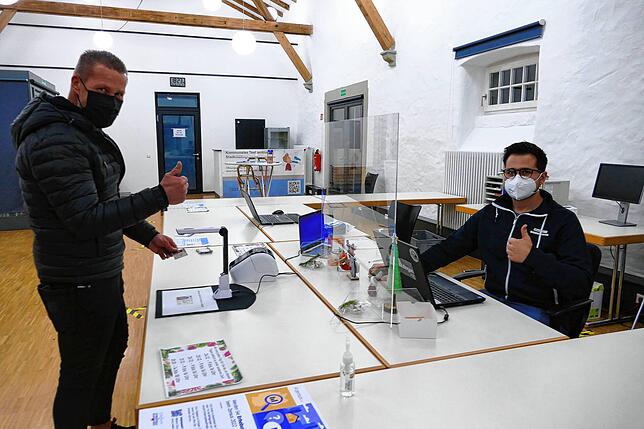 Mete Ünal (rechts) registriert am Laptop die Daten des Personalausweises, den Alexander Faak unter den Scanner hält. Und dann kann auch ...