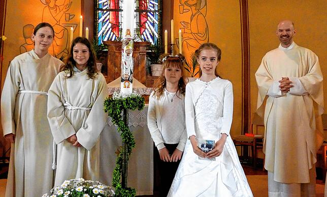 Die Ministranten mit den Kommunionkindern Elly Marlen Maske und Johanna Marie Schäuble neben der Osterkerze, rechts außen Pfarrer ...