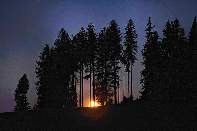 Der Erdbeermond hinter einem Bergwald in Bayern.
