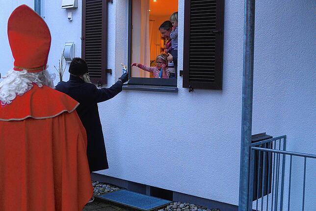 Mit Abstand kann Sarah das Geschenk persönlich annehmen und ihr Bild an den Nikolaus übergeben, das sie auf dem Foto noch ...