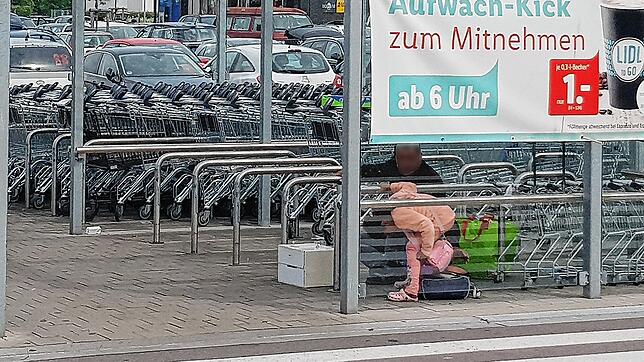 Ein Kind und ein Mann sitzen unter dem Dach des Einkaufswagendepots am Brennet-Areal mit einer Schale mit Kleingeld und hoffen auf ...