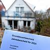 Böses Erwachen für die Bewohner? Ein Grundsteuerbescheid für das Jahr 2024 wird vor einem bebauten Privatgrundstück in Stuttgart ...