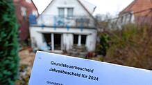 Böses Erwachen für die Bewohner? Ein Grundsteuerbescheid für das Jahr 2024 wird vor einem bebauten Privatgrundstück in Stuttgart ...