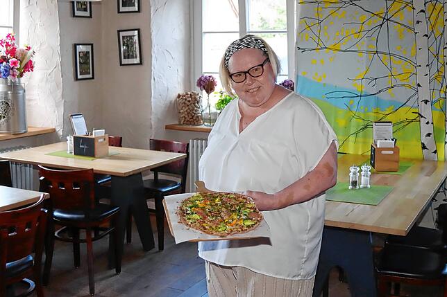 Wirtin Eeva Karjalainen serviert einen der Flammkuchen, für die viele Gäste eigens zum Gasthof „Breitbrunnen“ kommen.