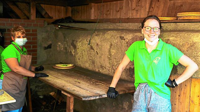 Elisabeth Feist mit Barbara Bruker-Wernet (hinten) beim Pizzabacken im hofeigenen Holzofen.