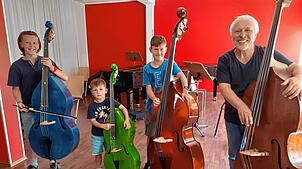 Nathanac, Aaron und Jonas (von links) wollen Kontrabass lernen. Mit Zenon Kazimierz-Strittmatter haben sie einen begeisterten Lehrer ...