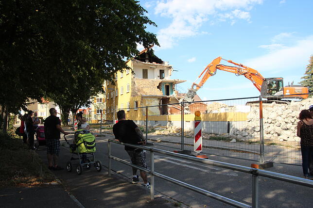 Anwohner haben sich in der Eintrachtstraße versammelt und verfolgen, wie das Haus Nummer 18 nach und nach abgerissen wird.