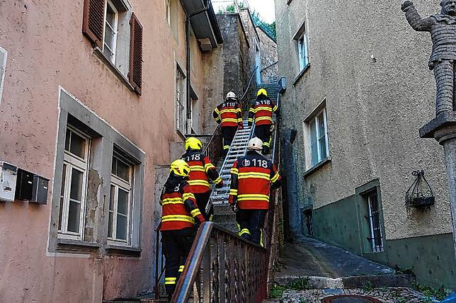 Schweizer Feuerwehrleute tragen 2022 bei einer Übung im deutschen Laufenburg auf einer engen Freitreppe eine Handleiter von der ...