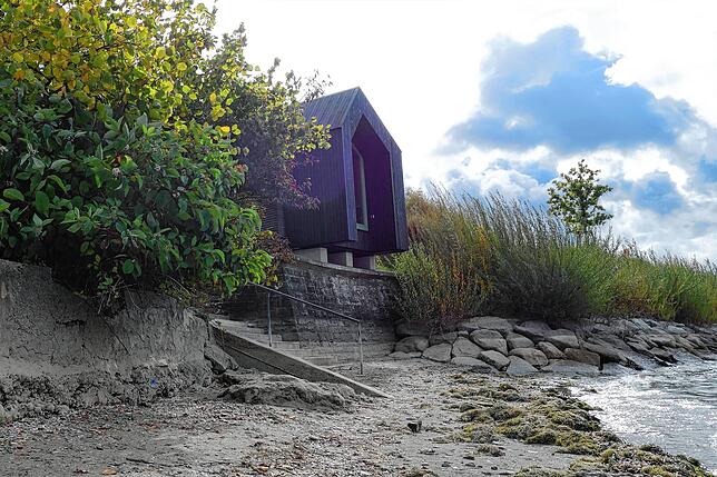Das Mini-Holzhaus hat einen ganz besonderen Platz mit einem kleinen Strand.