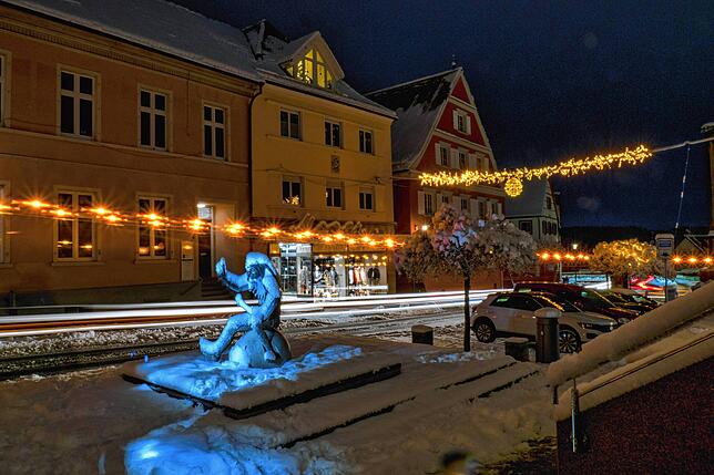 Der zugedeckte Hans Kuony-Brunnen beim Bürgerhaus in Stockach und die Weihnachtsbeleuchtung, die die Hauptstraße erleuchtet.